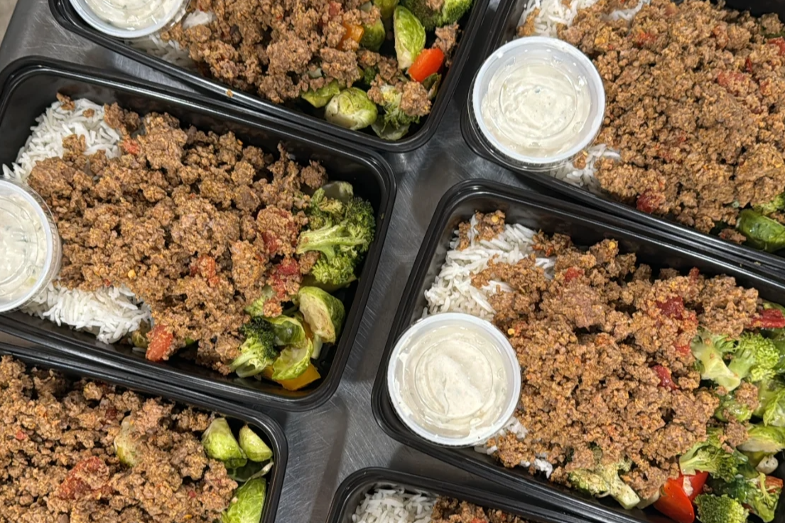 Fresh meal prep containers with seasoned ground beef, rice, and colorful vegetables